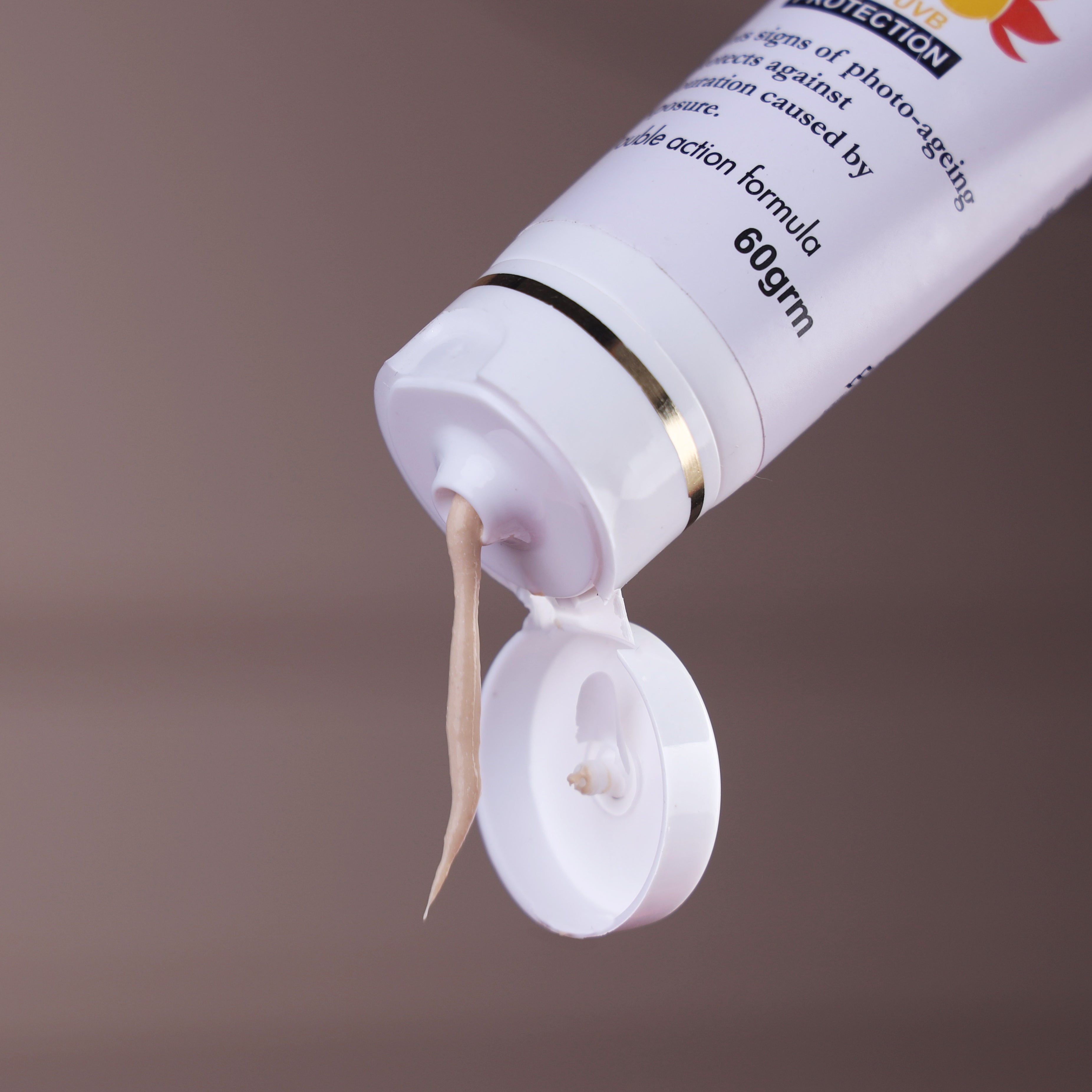 Close-up of skincare cream tube with beige lotion for face, 60gm, on neutral background.