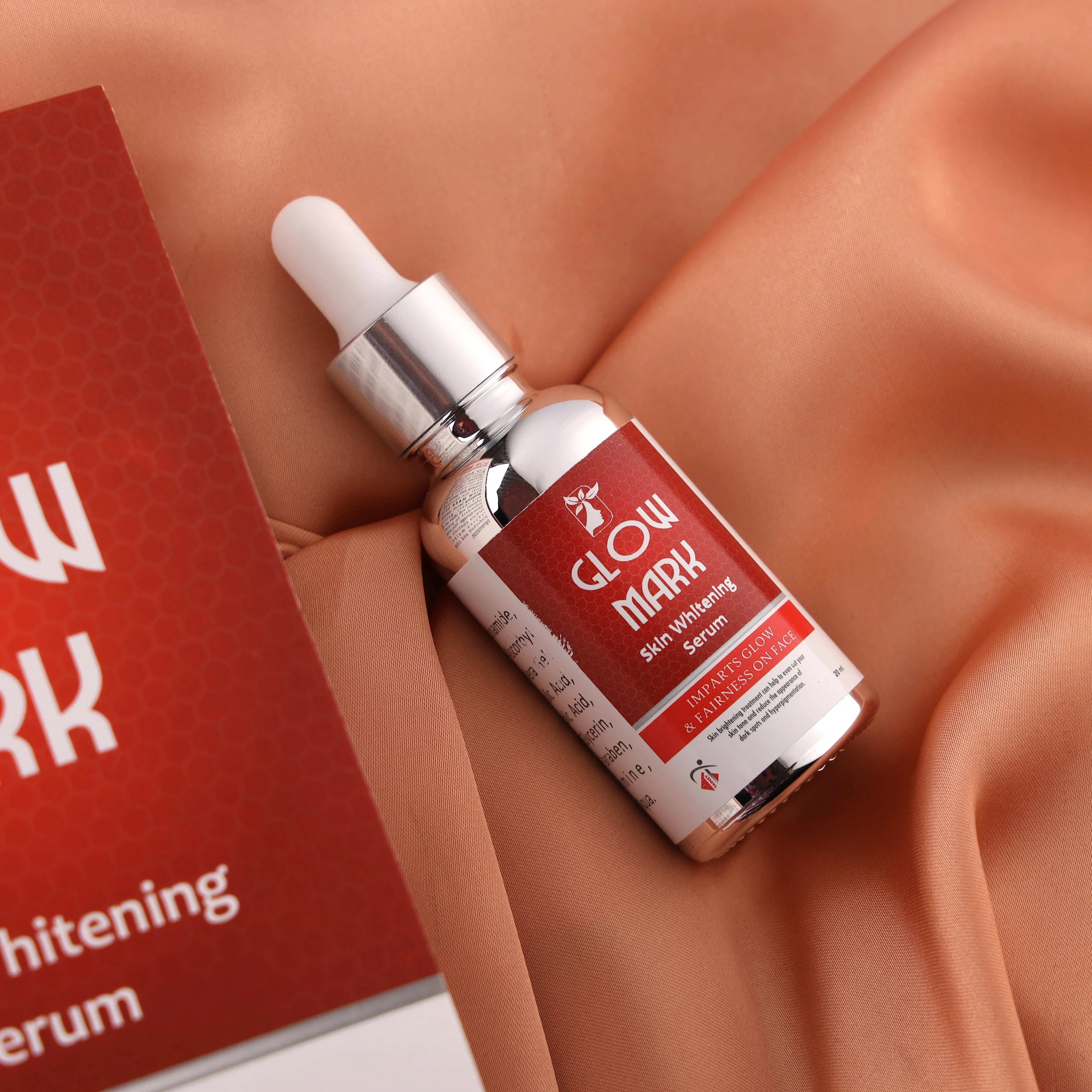 Glow Mark skin whitening serum bottle with dropper on peach fabric, skincare product