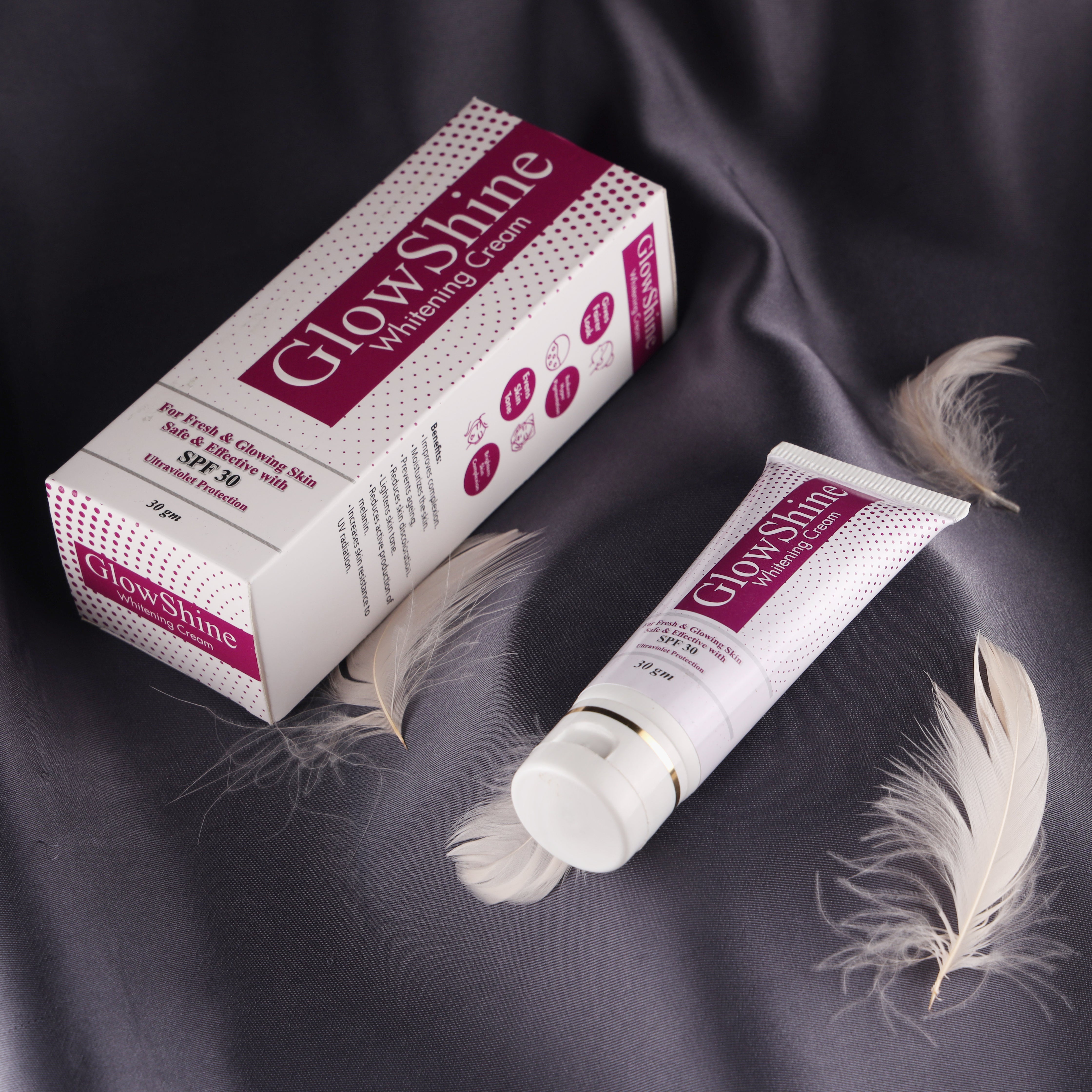 GlowShine whitening cream tube and box on silk fabric with feathers, skin care product