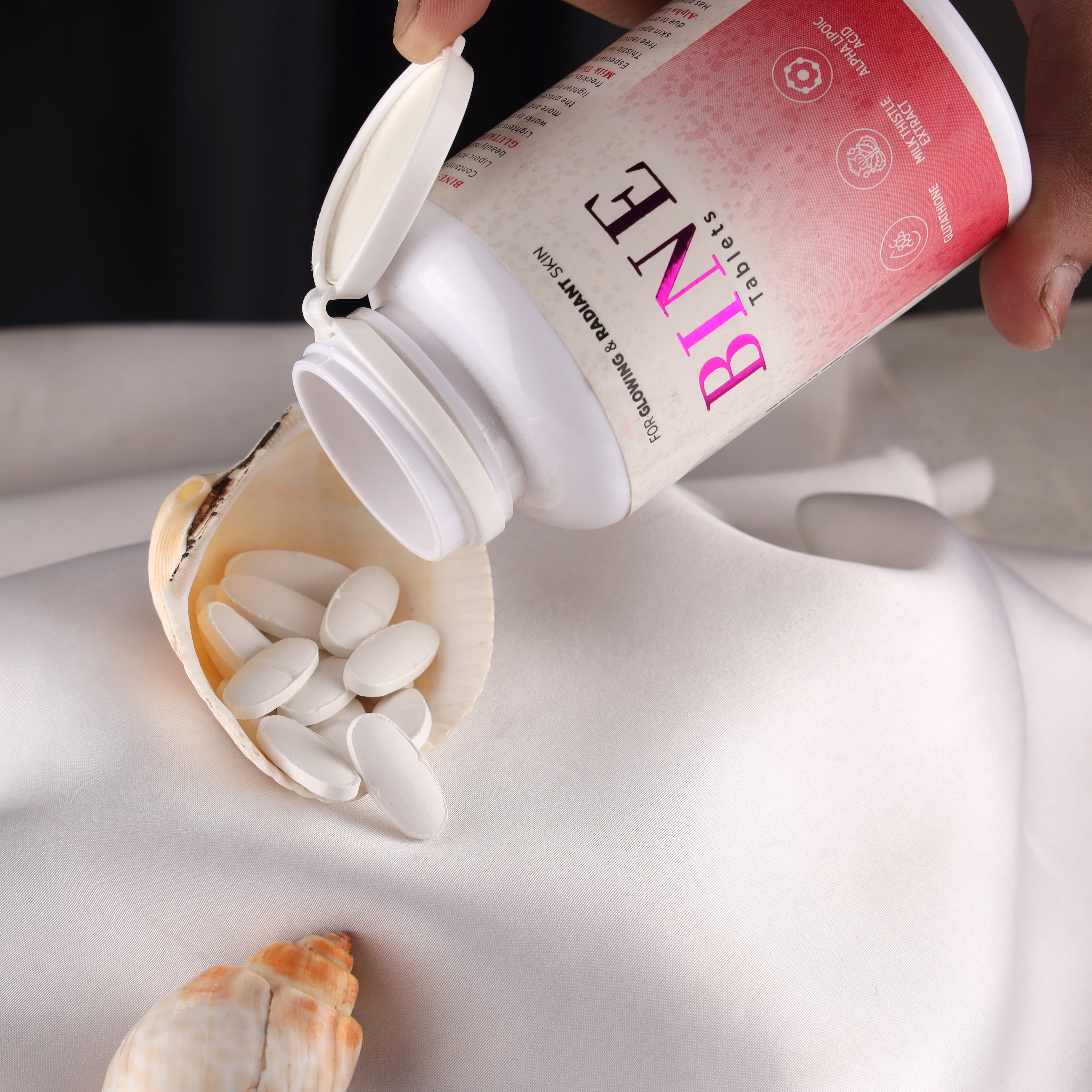 BINE tablets for glowing and radiant skin poured into a seashell on white fabric