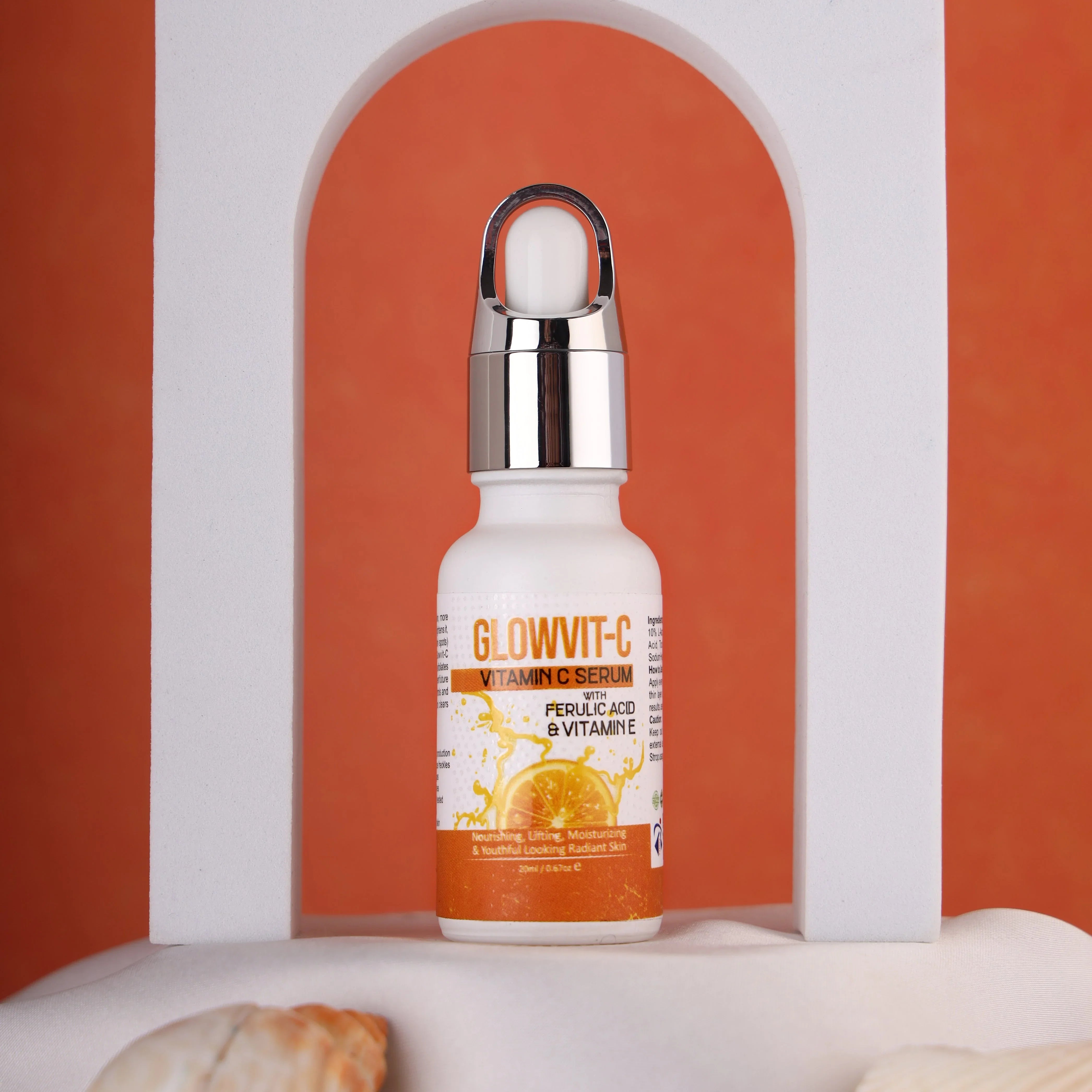 Glowwit-C Vitamin C serum bottle with ferulic acid on white display, orange backdrop