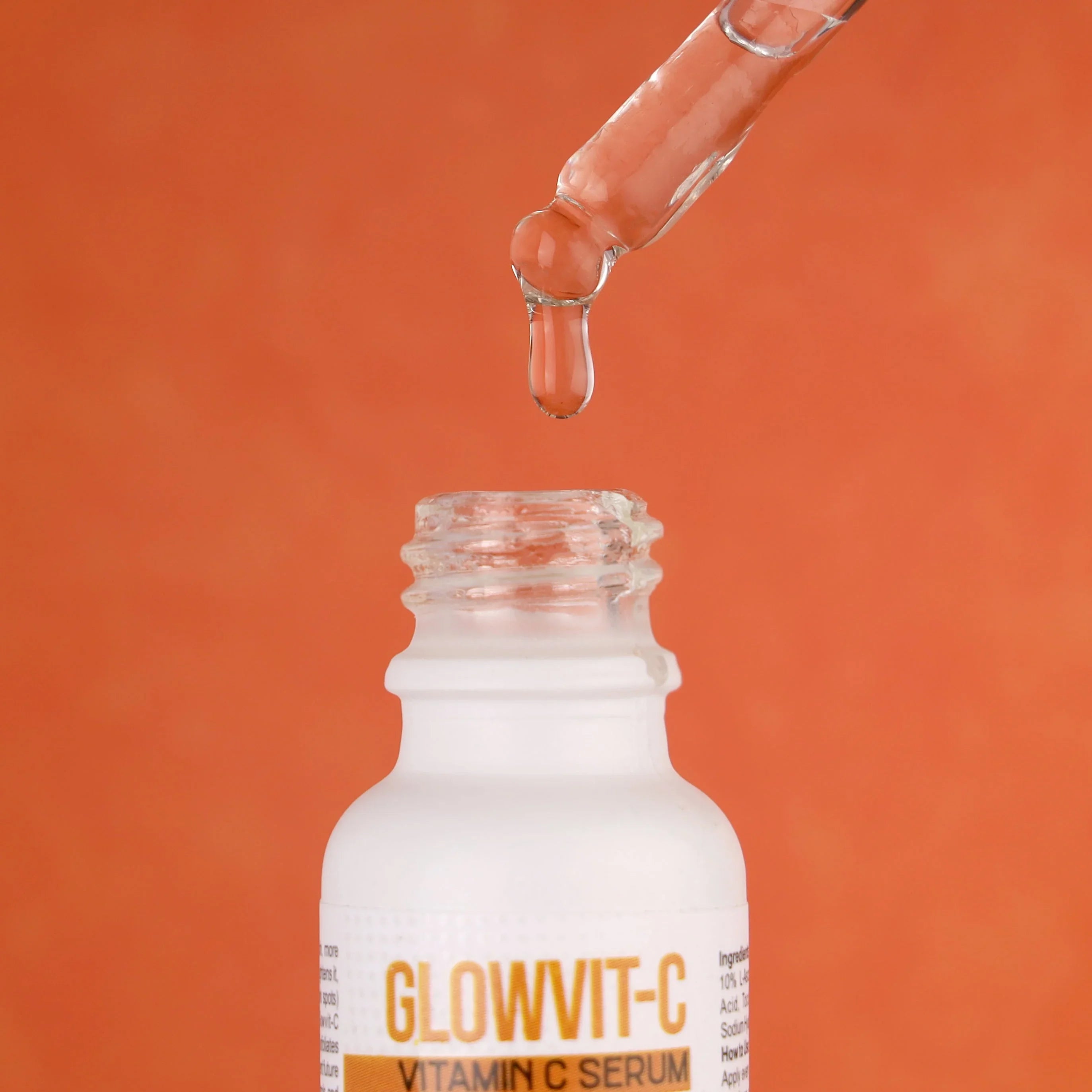 Glowvit-C Vitamin C serum dropper and bottle against orange background, skincare product