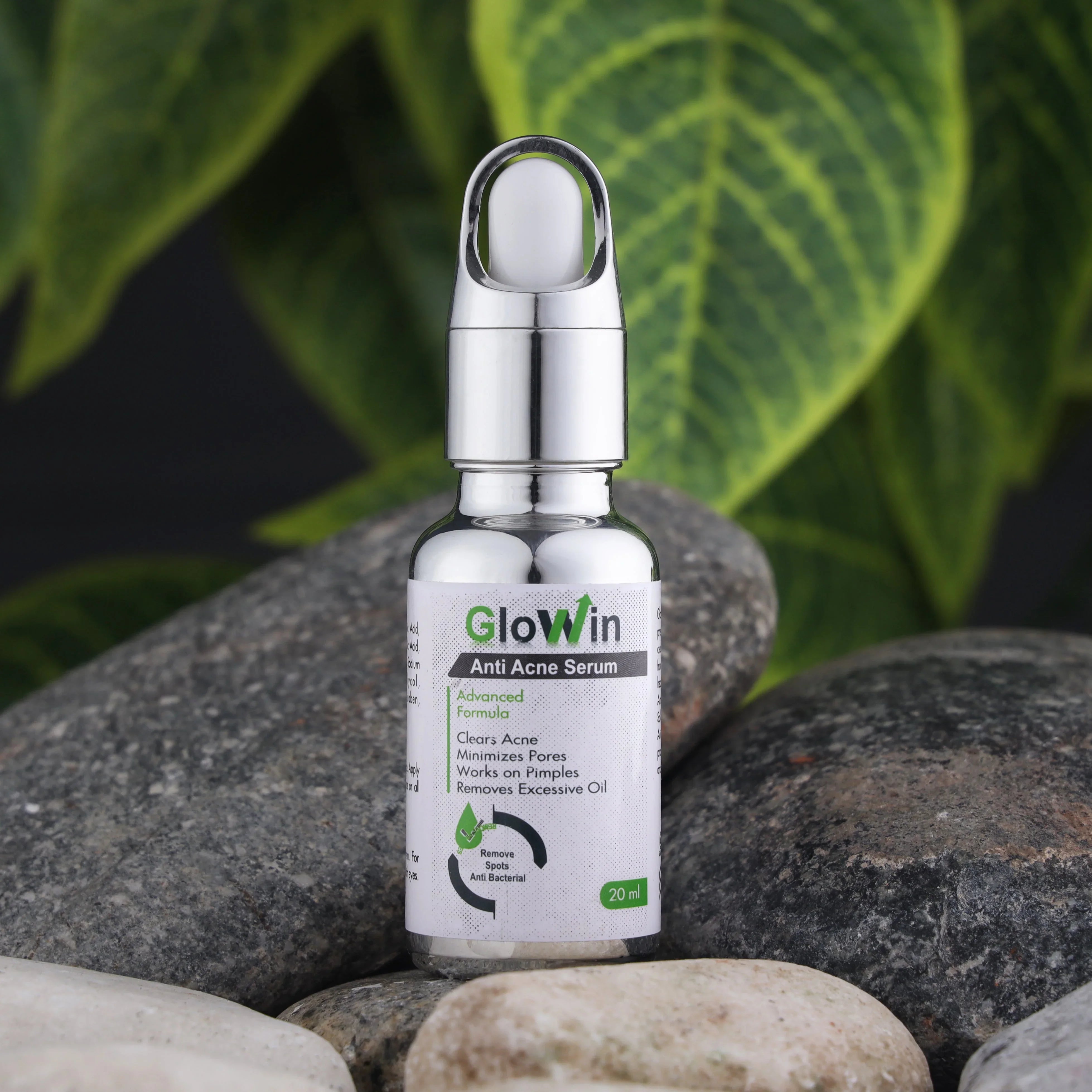 GlowWin anti acne serum bottle with silver cap on stones and green leaf background, skincare product