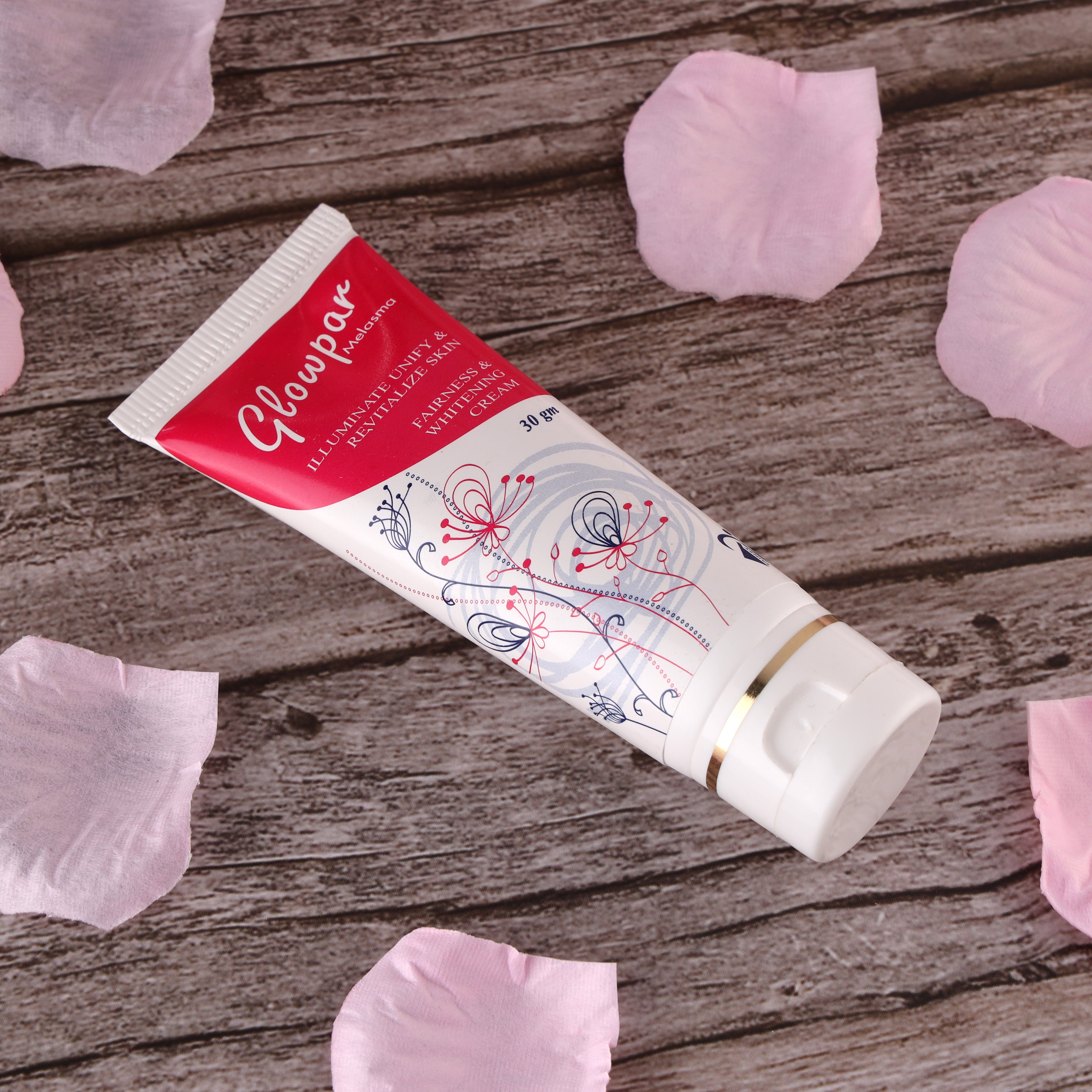 Tube of Glowpar Illuminating fairness cream on wooden surface with pink rose petals