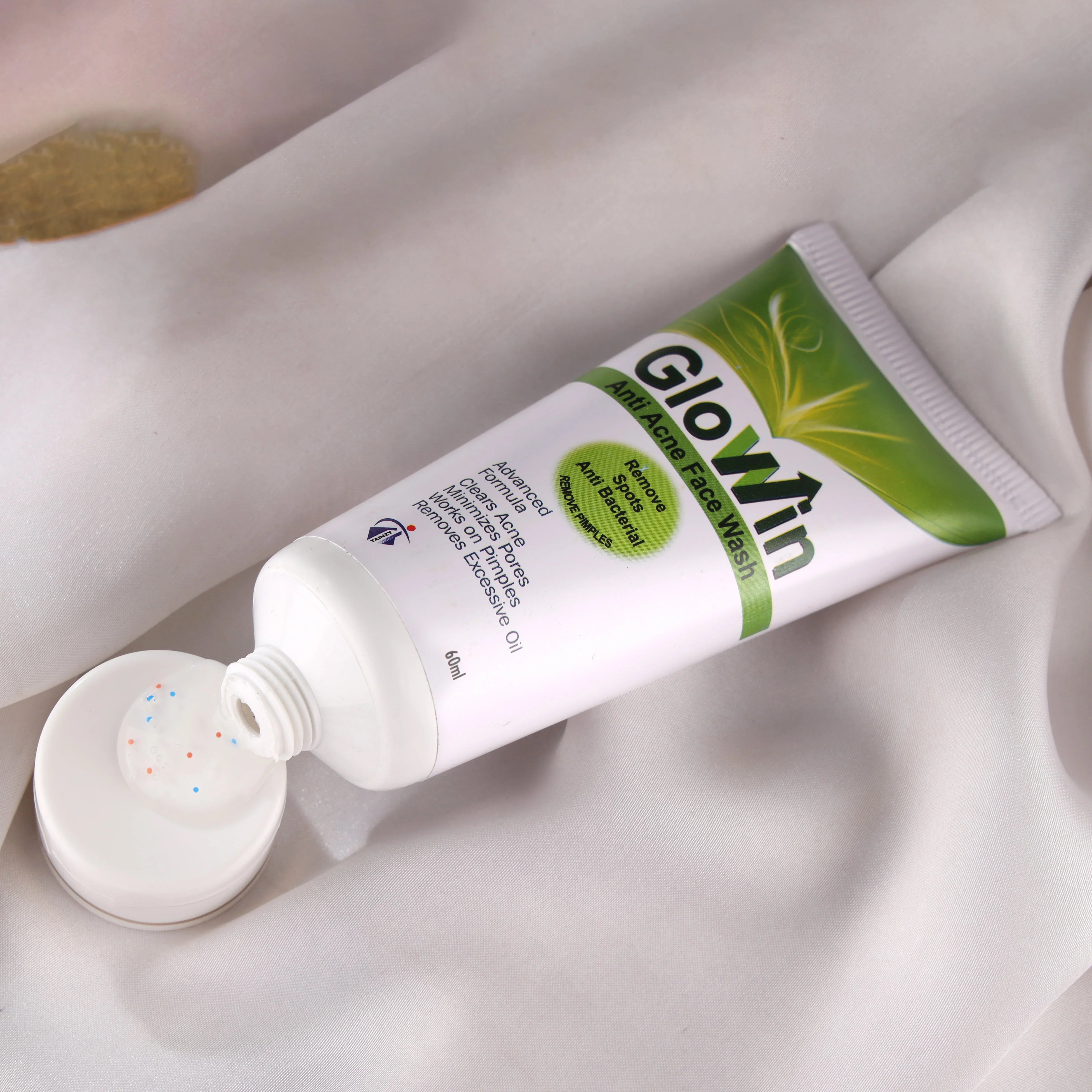 Glowin anti-acne face wash tube with dispensed gel on white cloth background
