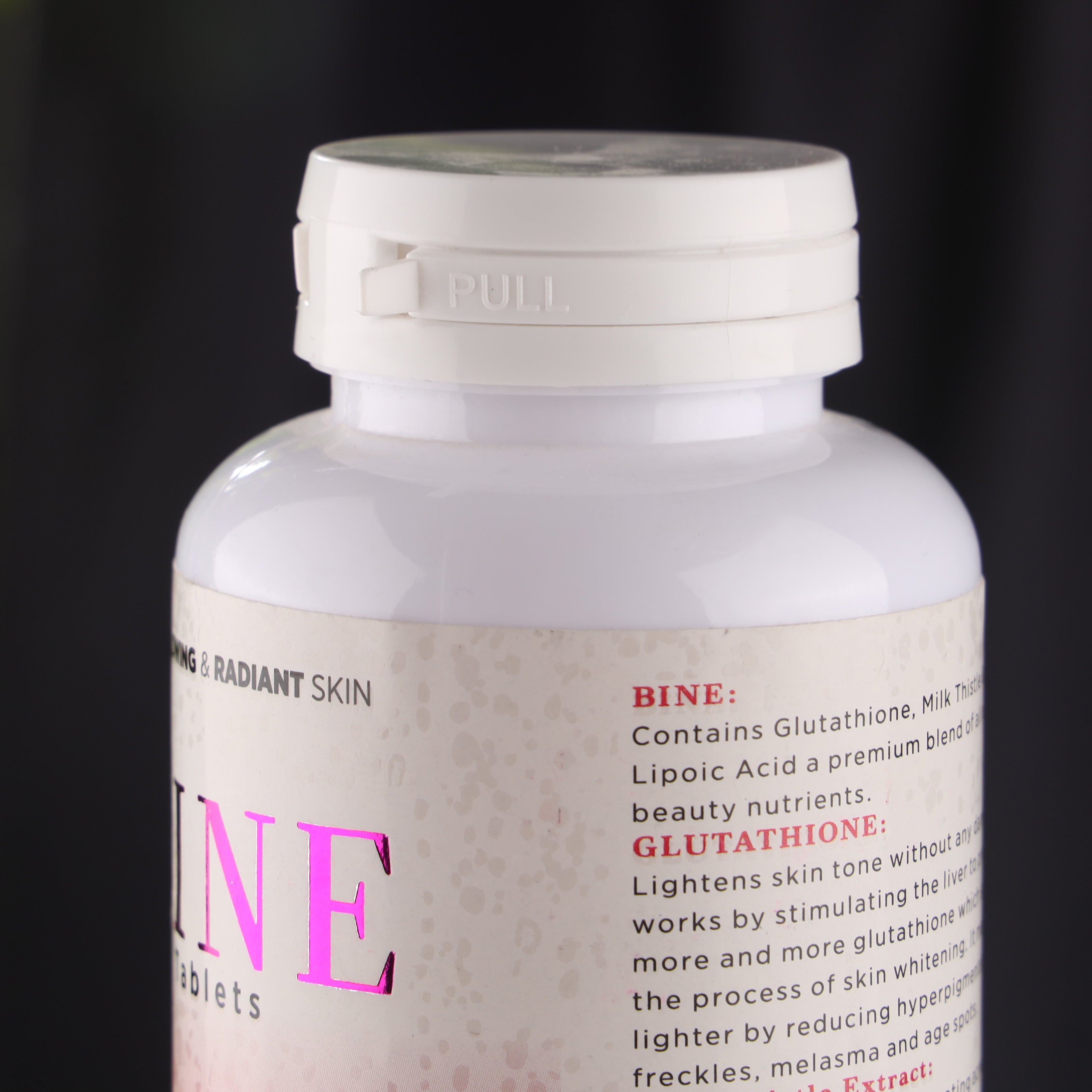 Close-up of a white skincare supplement bottle with label text about skin brightening ingredients.