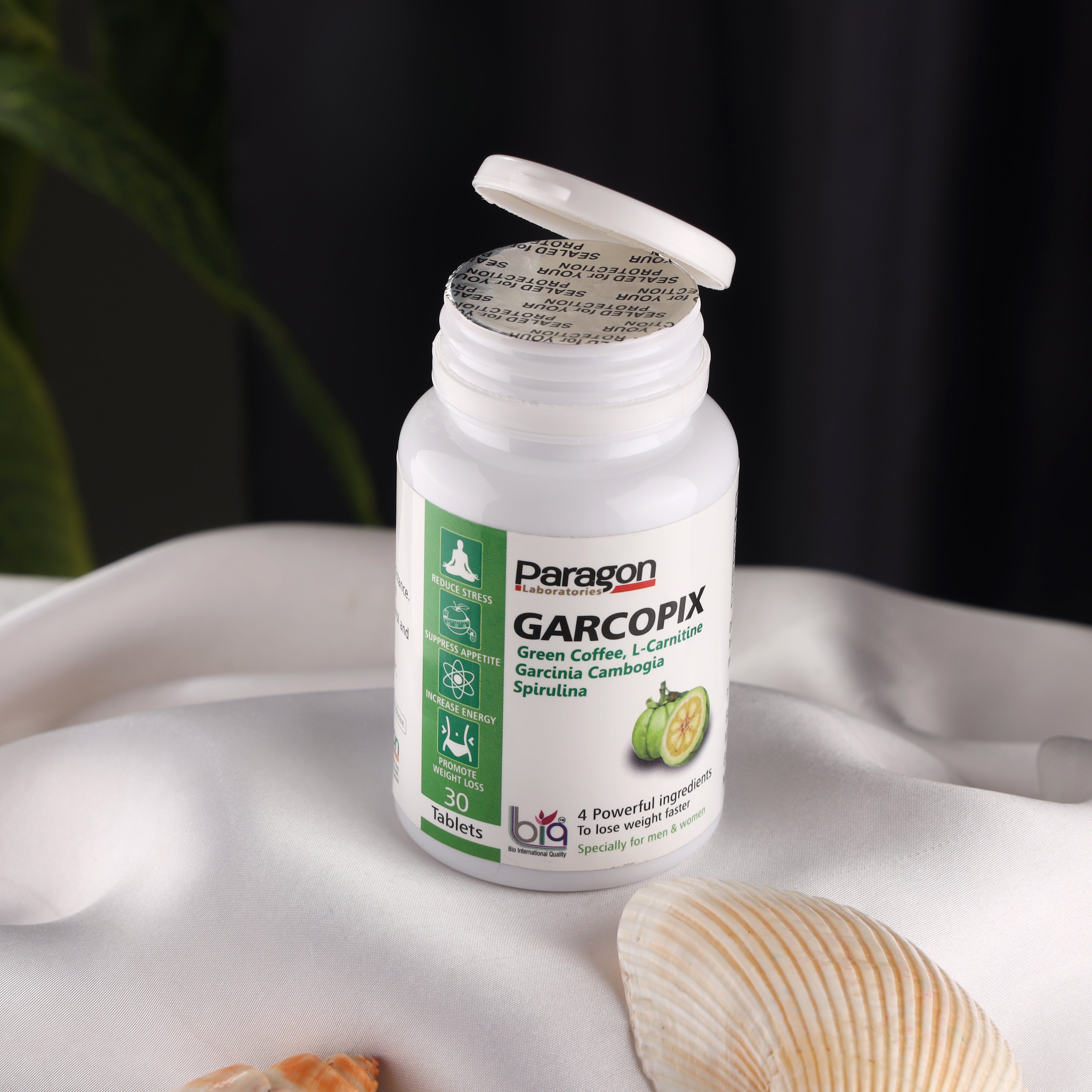 Garcopix dietary supplement bottle with green coffee, l-carnitine, and garcinia on white fabric