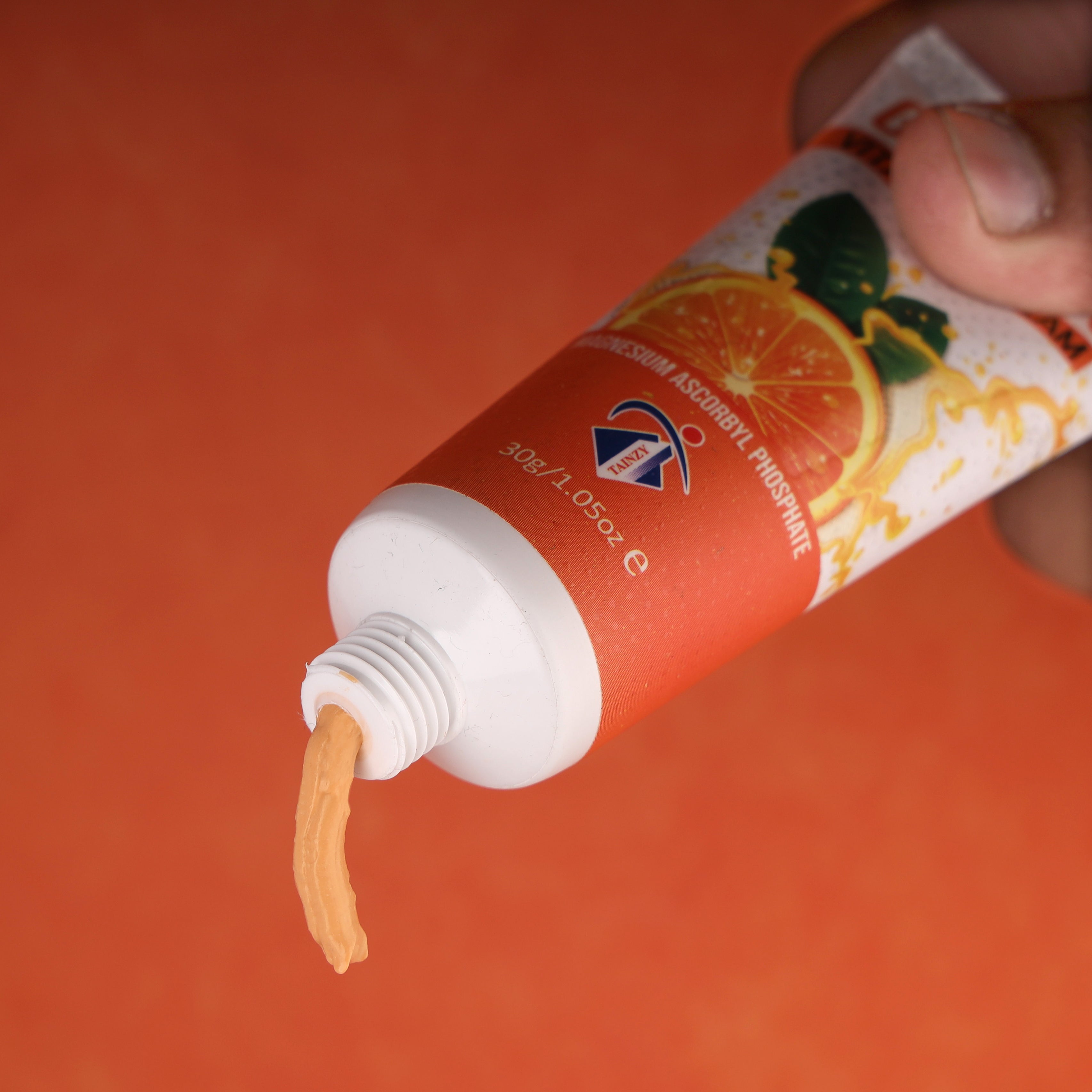 Vitamin C face cream tube with orange graphics and cream being squeezed out
